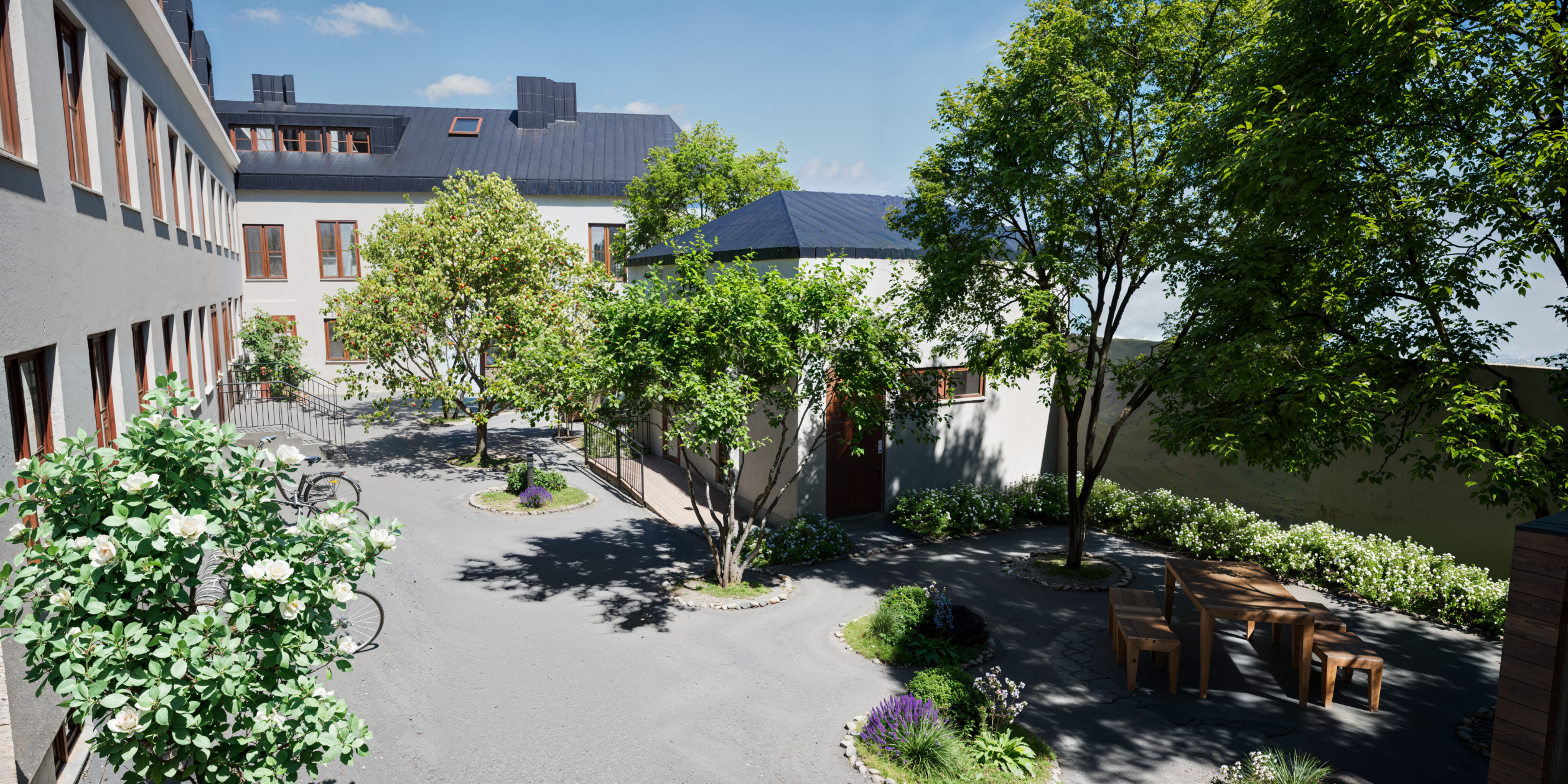 Exteriör av Kv. Leoparden i Stockholm med gröna träd, putsade fasader och bostäder i kulturhistorisk miljö.