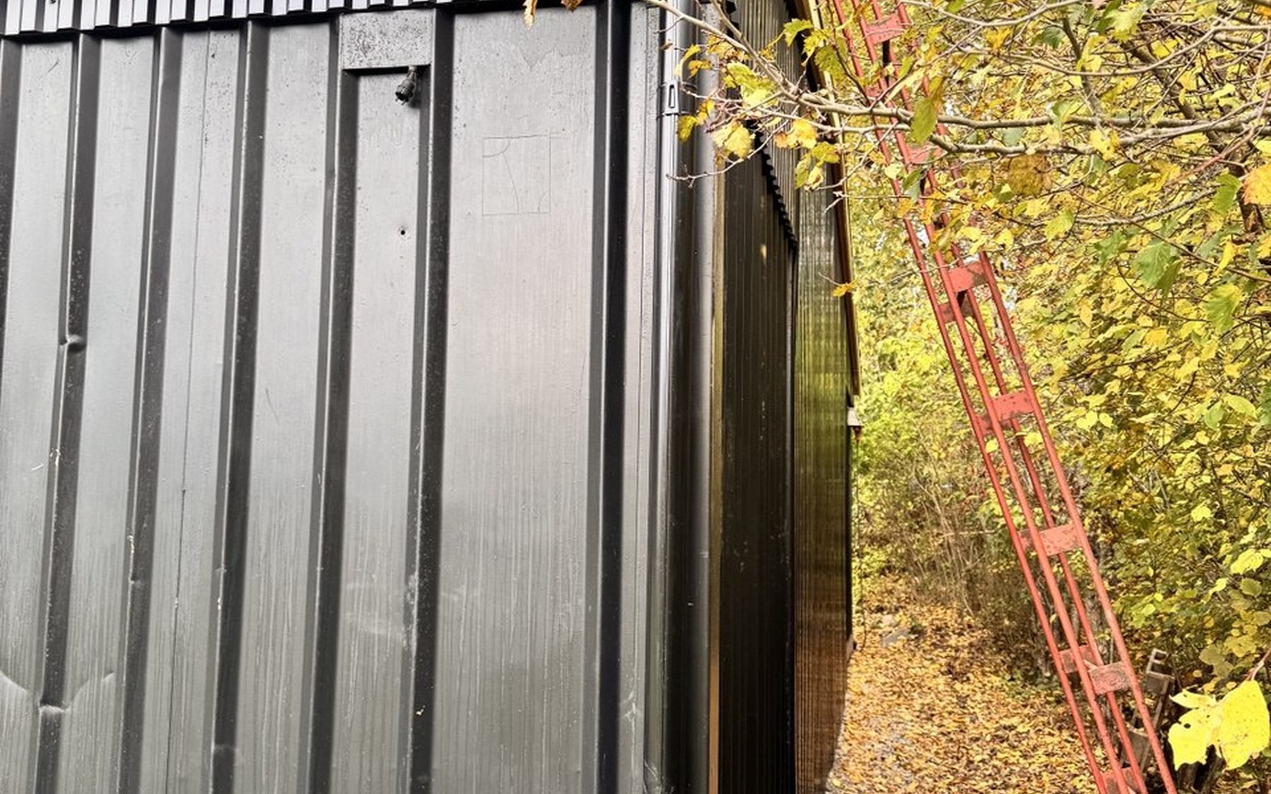 Detaljbild av garagebyggnadens mörka fasad och träkonstruktion