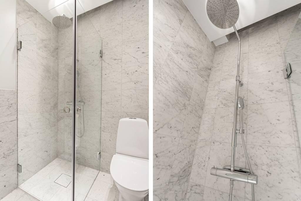 Närbild på duschhörnan i badrummet, som visar takduschen och den industriella glasväggen.